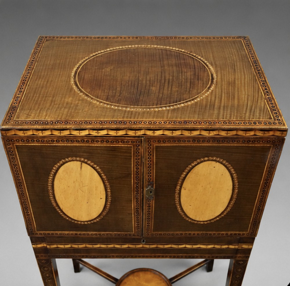 A late eighteenth-century Sheraton period harewood cabinet on stand featuring oval satinwood medallions, inlaid borders, slender square tapered legs, and a central stretcher tier. View III