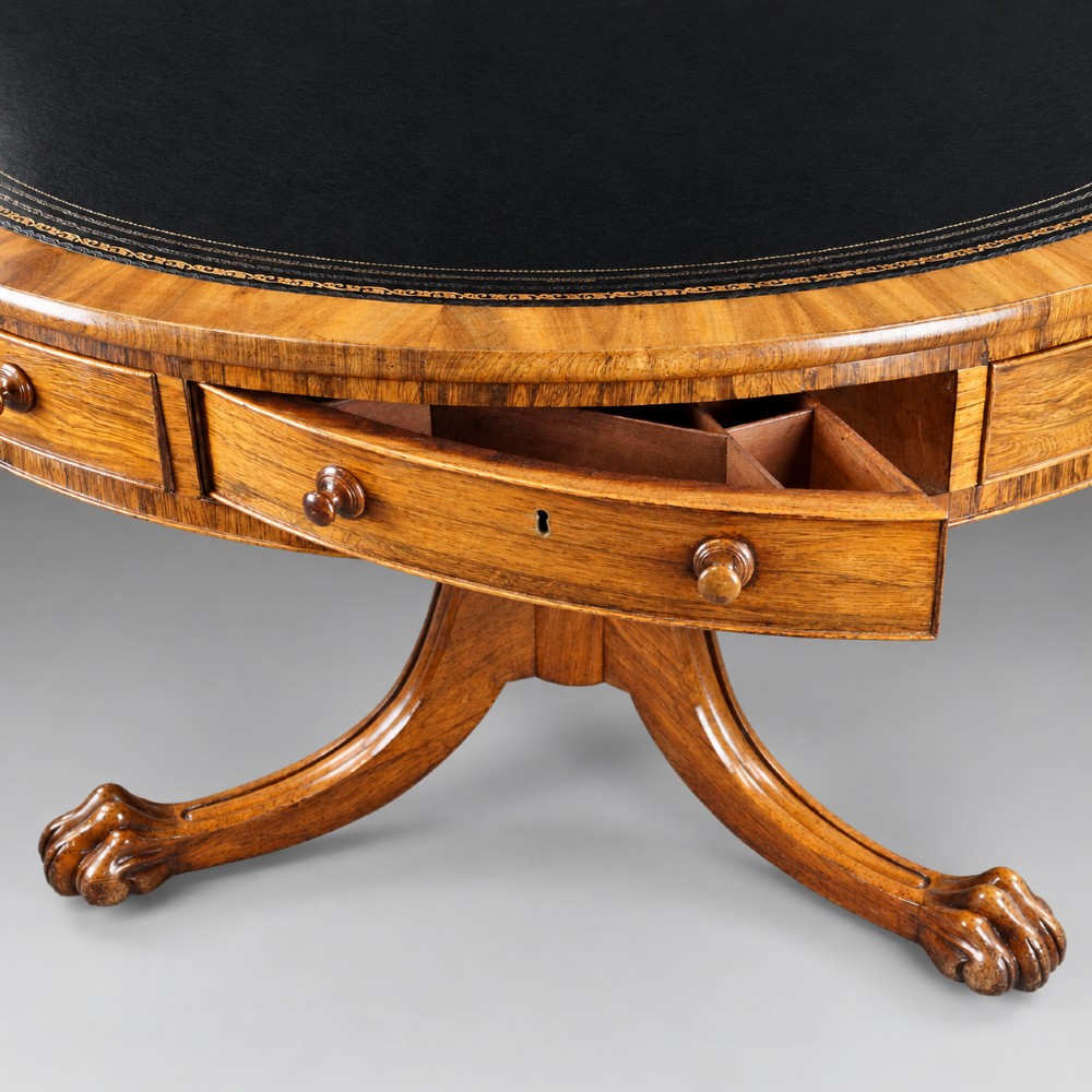 A circular Regency rosewood drum table featuring a black leather insert, perimeter drawers with turned knobs, and a central pedestal with splayed carved legs. View II