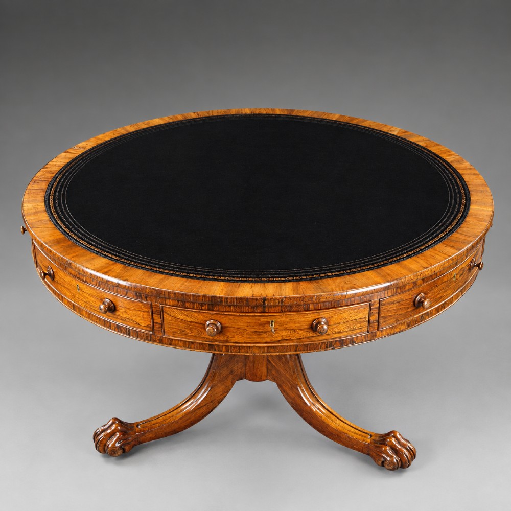 A circular Regency rosewood drum table featuring a black leather insert, perimeter drawers with turned knobs, and a central pedestal with splayed carved legs. View III