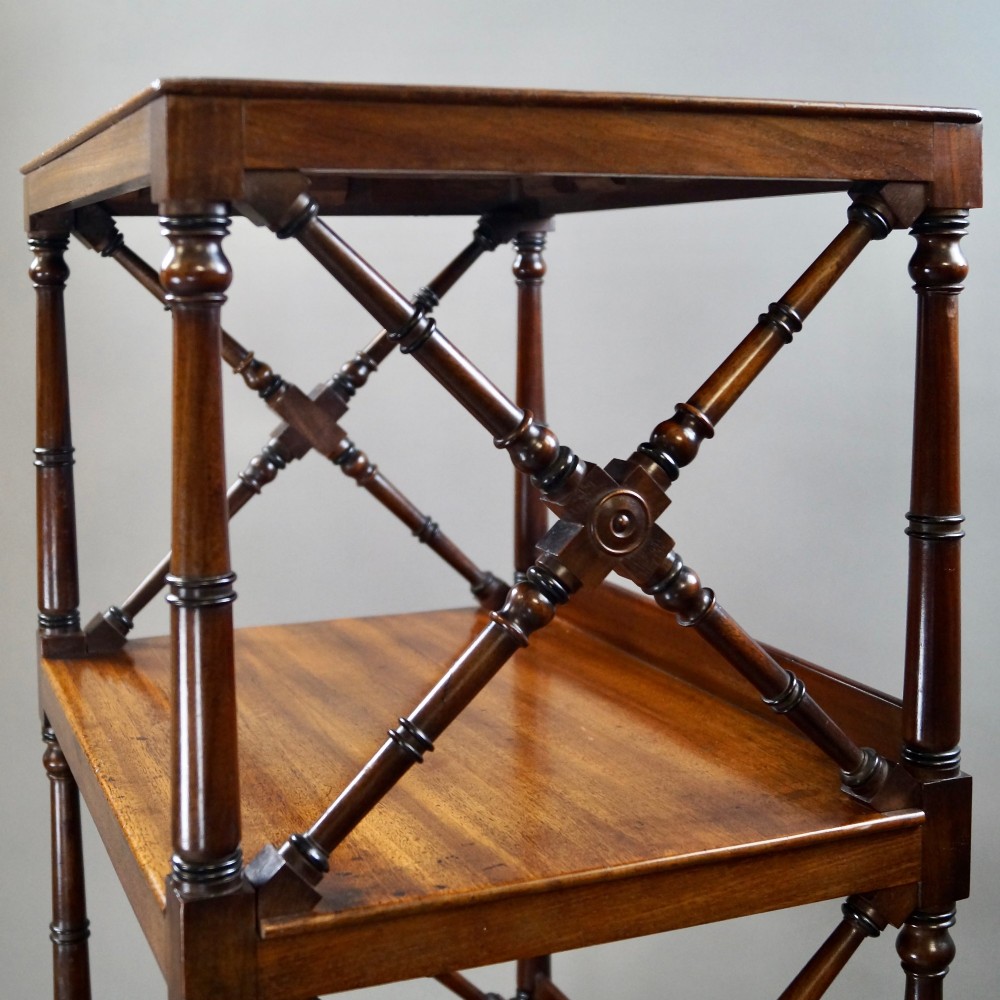 A tall George III mahogany four-tier whatnot featuring X-frame lattice sides on upper tiers, turned upright supports, a single drawer with a brass knob, and brass castors. View III