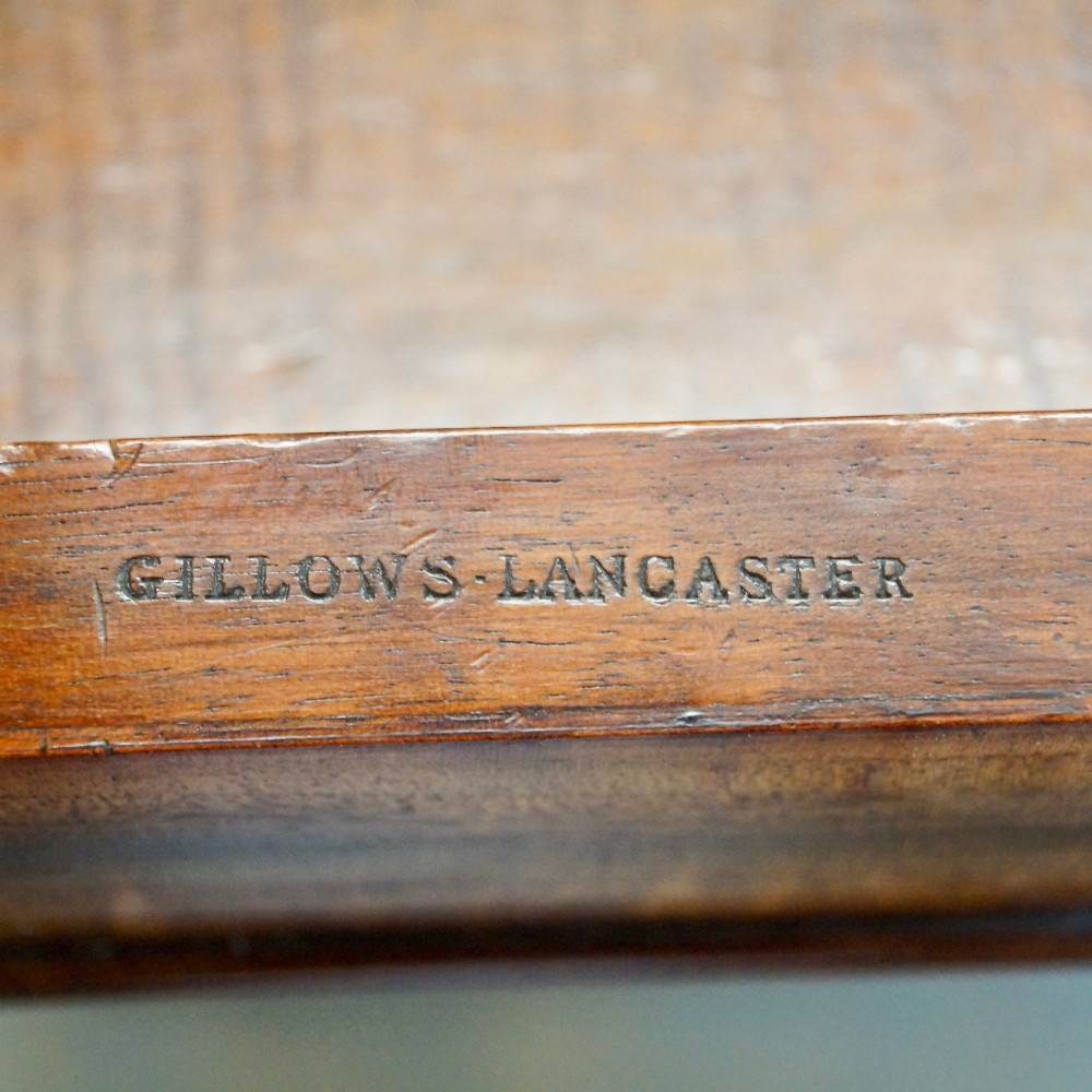 An antique flame mahogany Davenport desk featuring a slanted leather writing surface, perforated brass gallery, side drawers with turned brass knob handles, and compressed bun feet. View VII