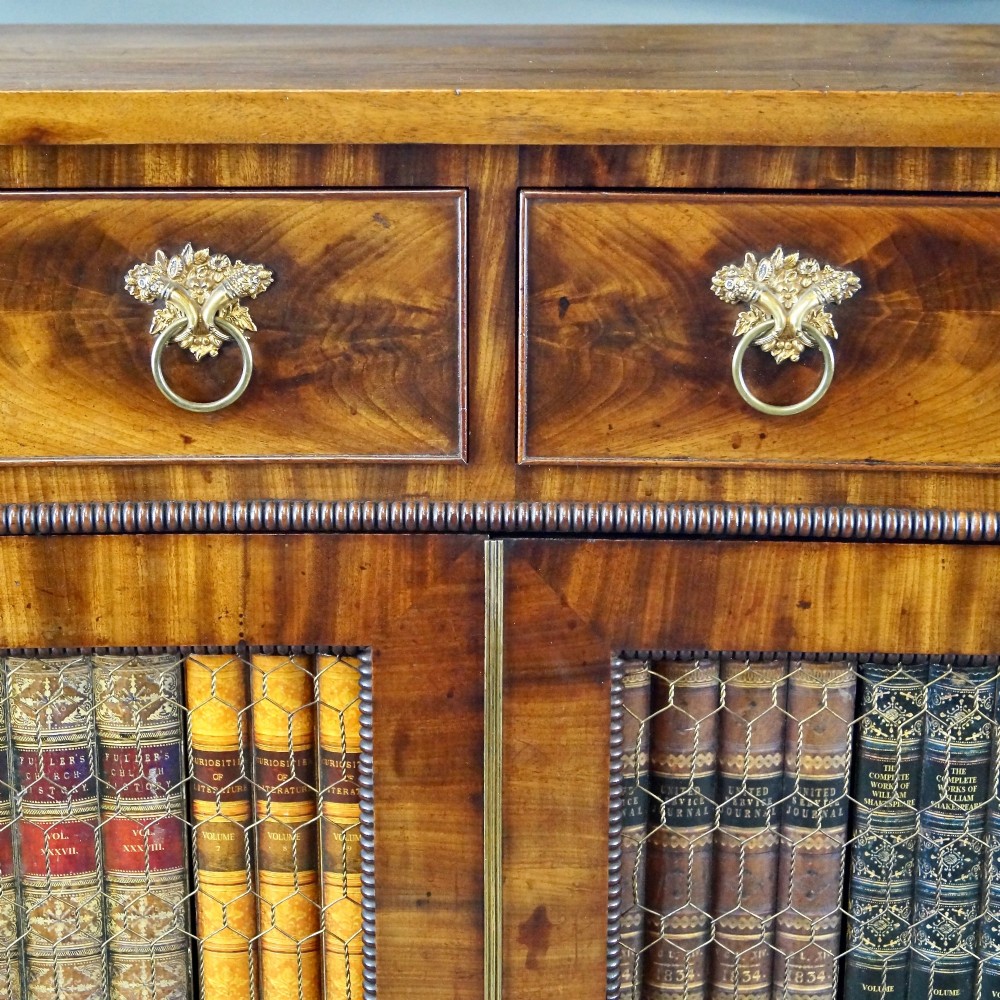 A William IV mahogany side cabinet featuring a concave front, two drawers with circular brass drop handles, and two lower mesh wire grille doors flanked by spiral-turned columns. View III