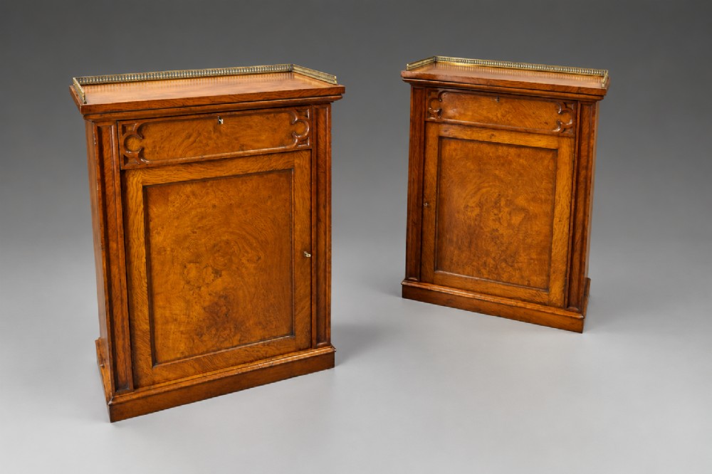 A pair of warm brown Gothic Revival wooden side cabinets featuring carved top drawers, single panel doors, and brass gallery rails along the tops. View III