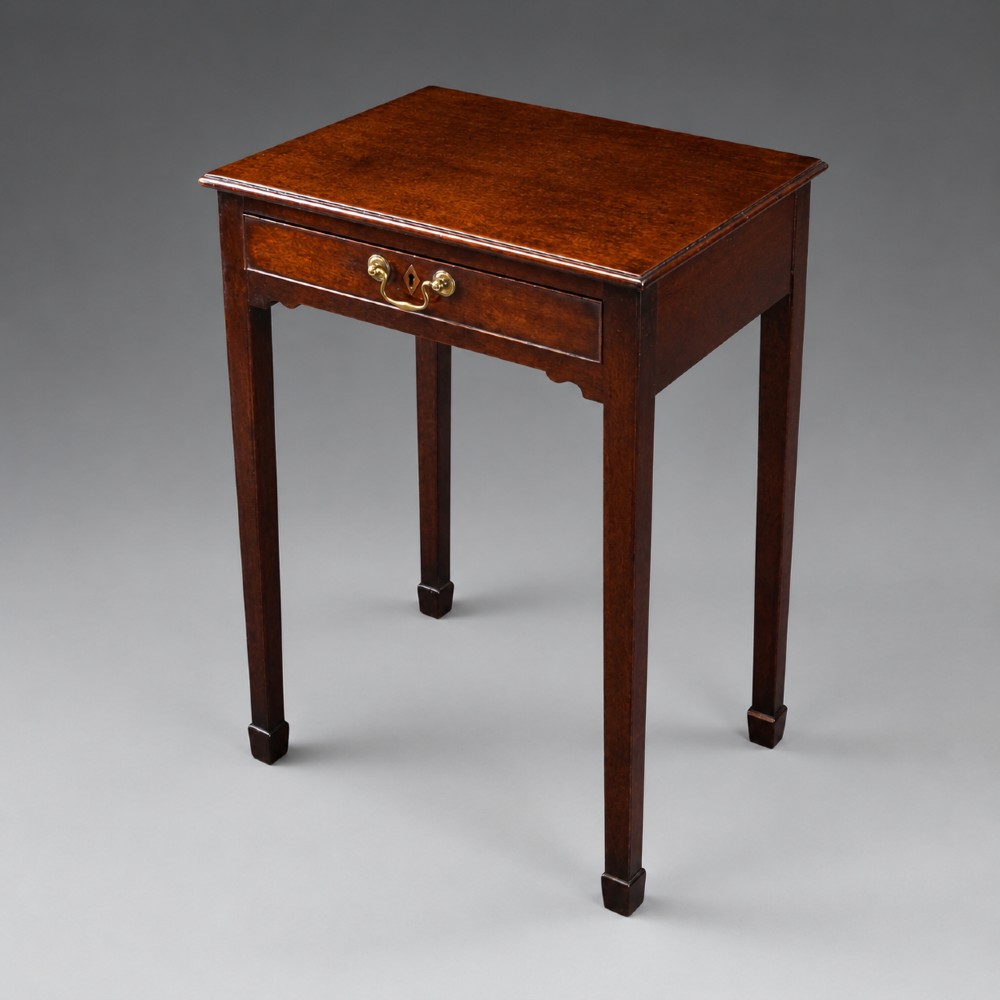 A George III mahogany side table featuring a single drawer with a central brass handle, supported by four tapered square legs. View II