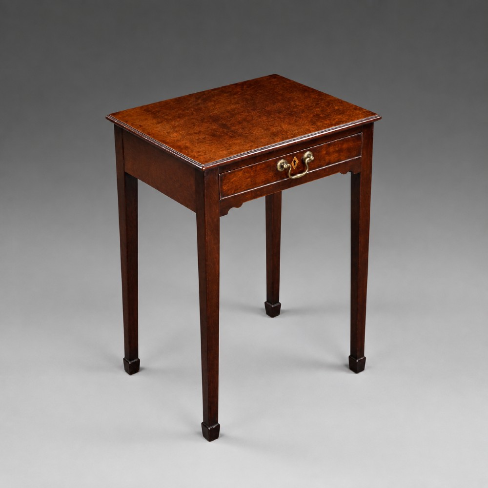 A George III mahogany side table featuring a single drawer with a central brass handle, supported by four tapered square legs. View V