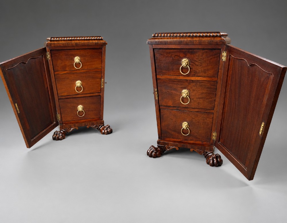 A pair of antique Regency flame mahogany pedestals featuring carved beadwork, framed door panels, and prominent carved lion paw feet. View II