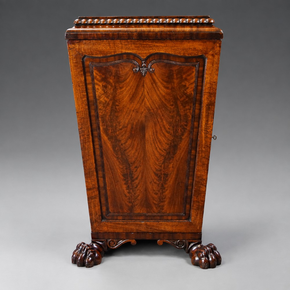 A pair of antique Regency flame mahogany pedestals featuring carved beadwork, framed door panels, and prominent carved lion paw feet. View III