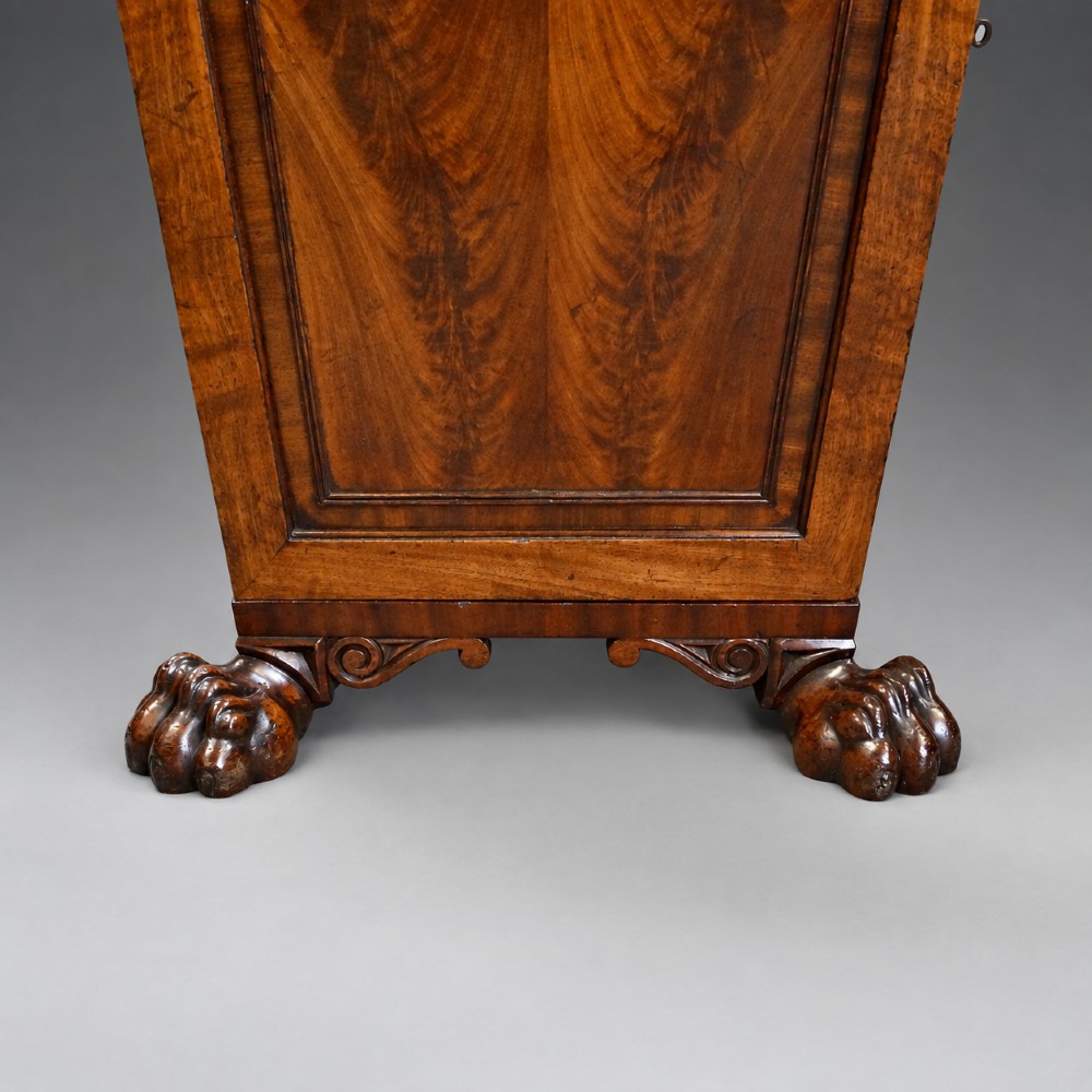 A pair of antique Regency flame mahogany pedestals featuring carved beadwork, framed door panels, and prominent carved lion paw feet. View V