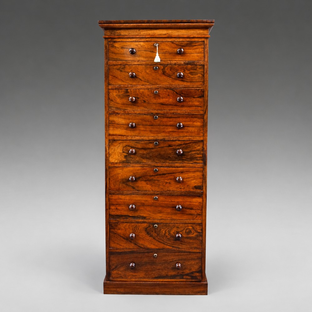 A tall, narrow antique rosewood chest of nine graduated drawers featuring turned wooden knobs and highly figured timber grain.