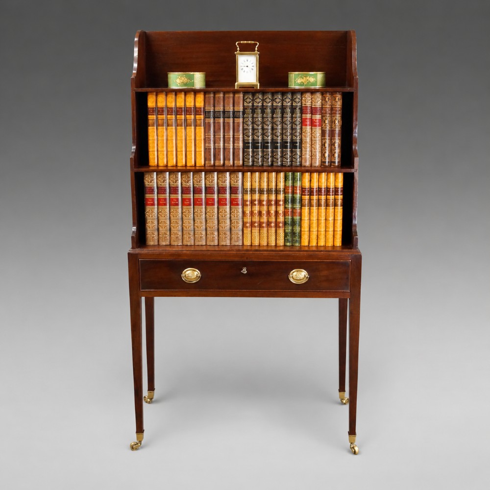 A George III mahogany waterfall bookcase with graduated open shelves, a single base drawer, side brass handles, and tapered square legs on castors. View II
