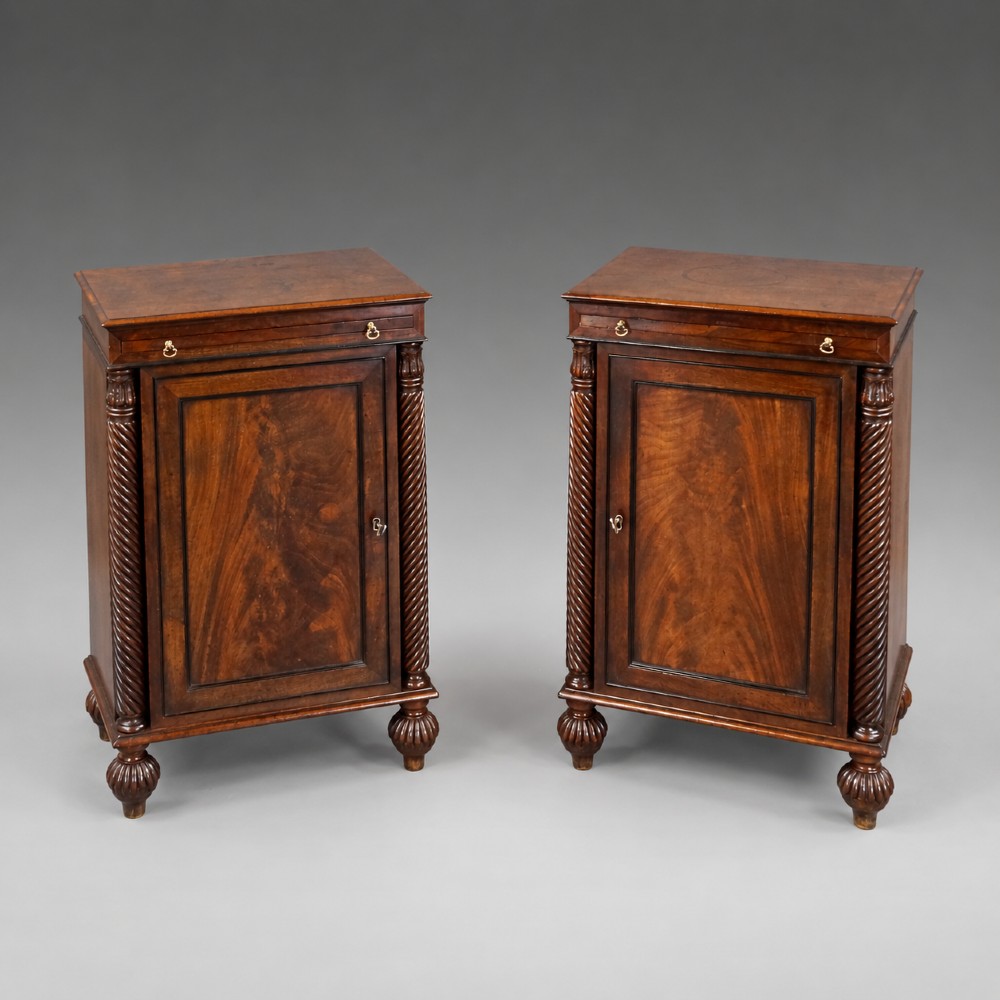 A pair of antique mahogany bedside cupboards with flame mahogany panel doors flanked by spiral-twist columns and supported by lobed bun feet. View V