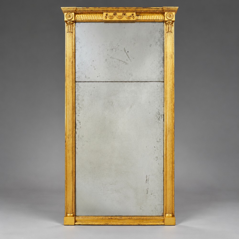 A tall rectangular George III giltwood pier mirror with fluted pilasters, a central drapery swag frieze, and a two-section mirror plate.
