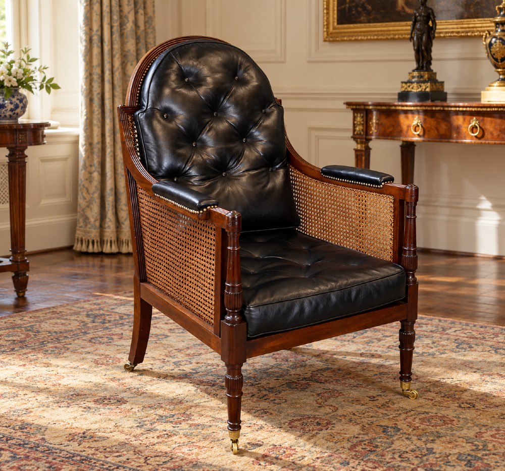 A Regency mahogany bergere armchair featuring woven cane side panels, button-tufted black leather upholstery, reeded turned front legs, and brass castors. View II