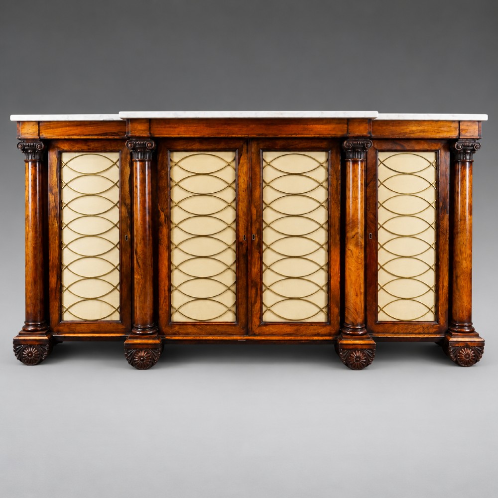 A Regency four-door rosewood side cabinet with a white marble top, carved columns, and brass lattice panels over fabric doors.