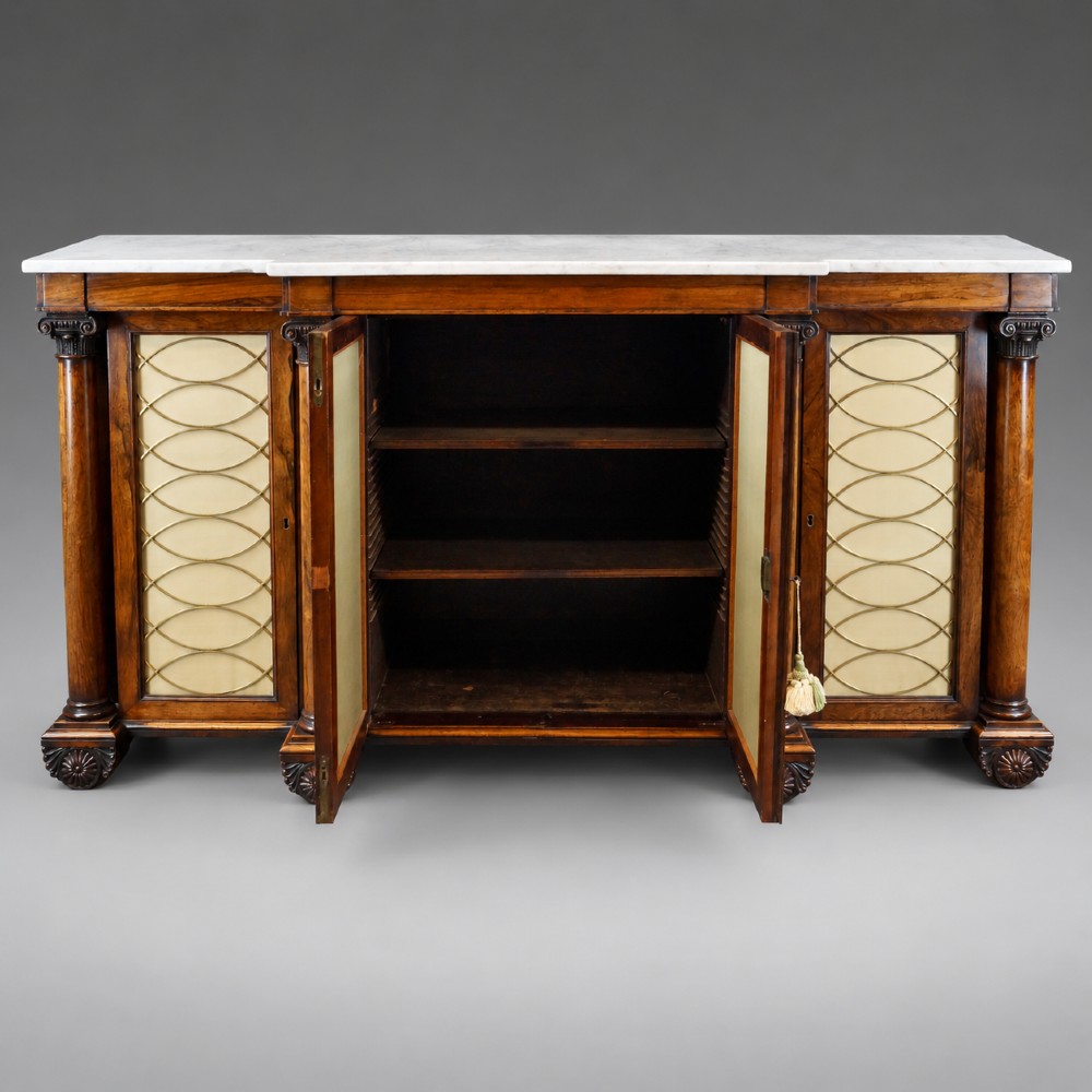A Regency four-door rosewood side cabinet with a white marble top, carved columns, and brass lattice panels over fabric doors. View VI