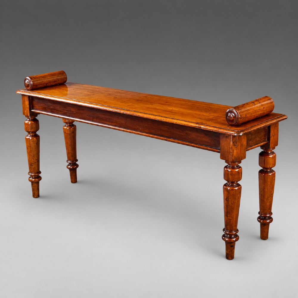 A nineteenth-century mahogany window bench featuring a long rectangular seat with raised scroll ends, supported by four turned legs. View II