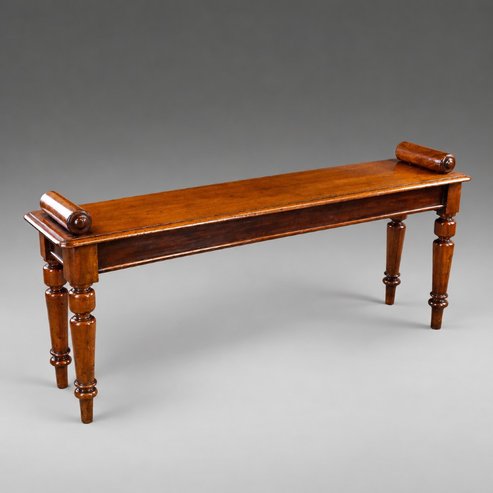 A nineteenth-century mahogany window bench featuring a long rectangular seat with raised scroll ends, supported by four turned legs. View IV