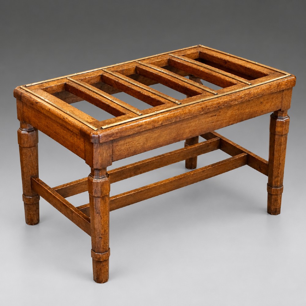 A late nineteenth-century oak luggage stand featuring brass-capped top slats, turned legs, and lower H-stretchers against a grey background.