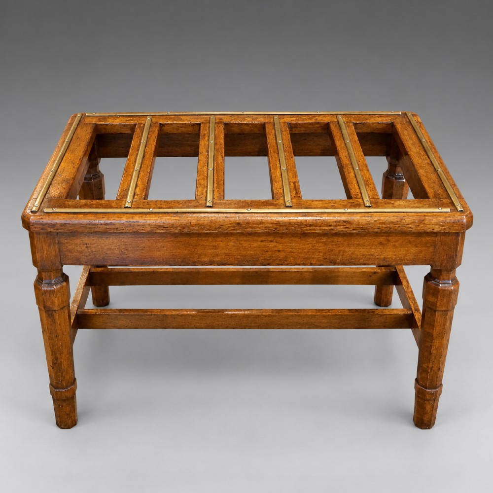 A late nineteenth-century oak luggage stand featuring brass-capped top slats, turned legs, and lower H-stretchers against a grey background. View IV