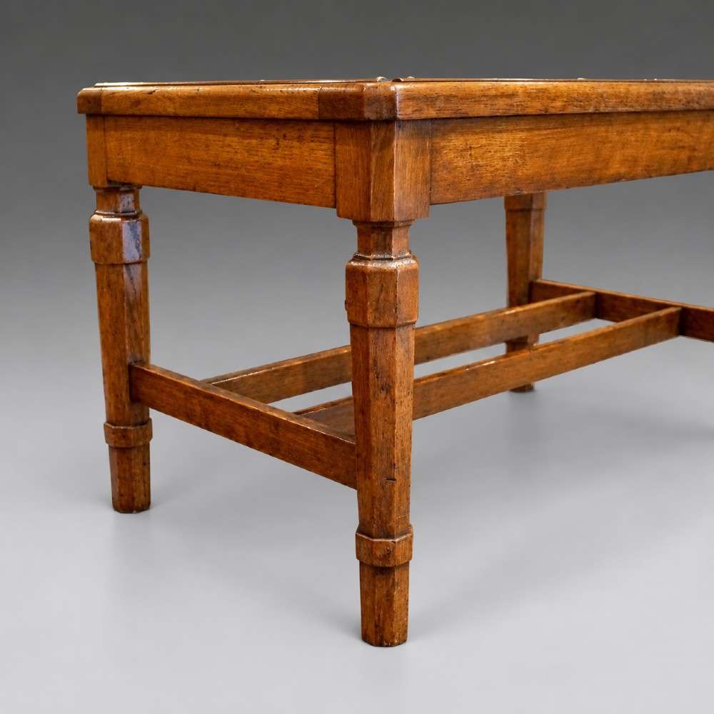 A late nineteenth-century oak luggage stand featuring brass-capped top slats, turned legs, and lower H-stretchers against a grey background. View V