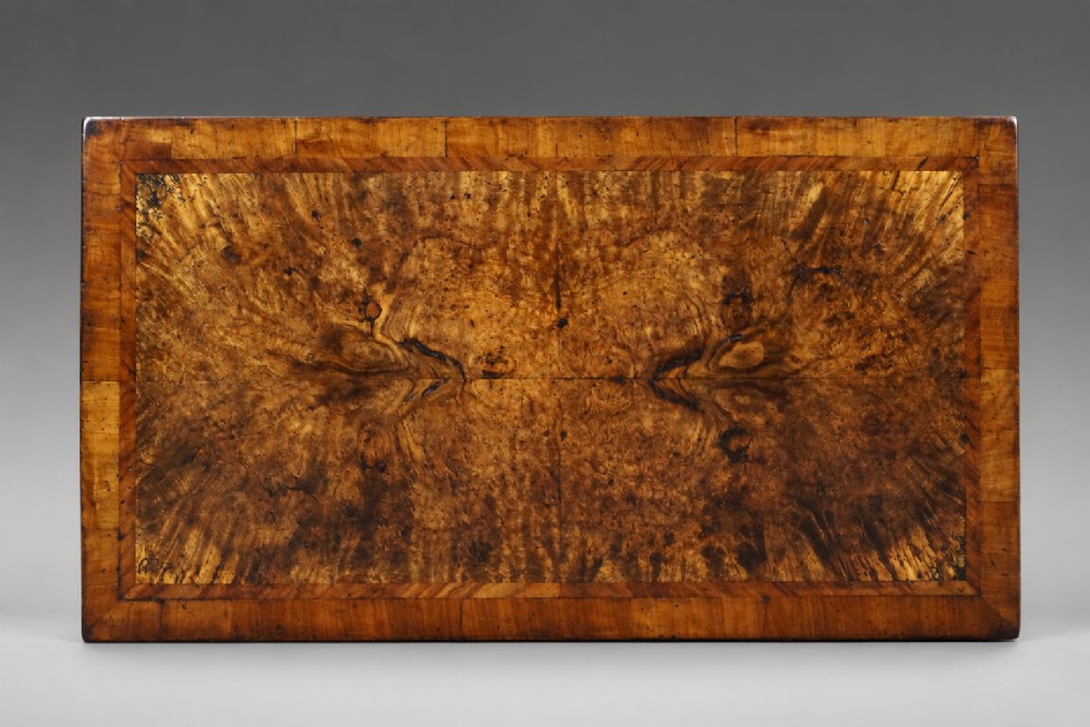 A Queen Anne burr walnut chest of drawers featuring two short over three long graduated drawers with brass drop handles and bun feet. View II