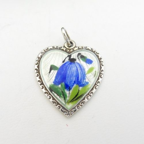 fig 1. A heart-shaped sterling silver pendant featuring white guilloche enamel with a hand-painted blue bluebell motif surrounded by a beaded border.