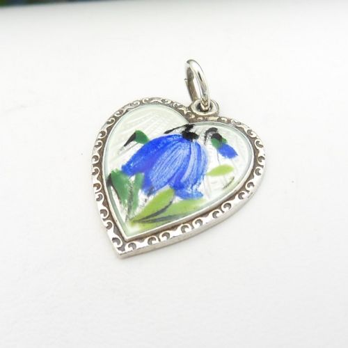 A heart-shaped sterling silver pendant featuring white guilloche enamel with a hand-painted blue bluebell motif surrounded by a beaded border. View IV