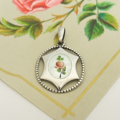 An antique sterling silver pendant containing a white guilloche enamel oval decorated with a painted pink rose, enclosed within a star-shaped silver motif and beaded circular outer border. View III