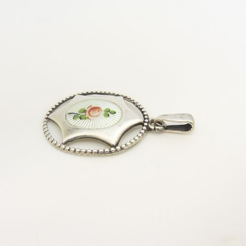 An antique sterling silver pendant containing a white guilloche enamel oval decorated with a painted pink rose, enclosed within a star-shaped silver motif and beaded circular outer border. View V