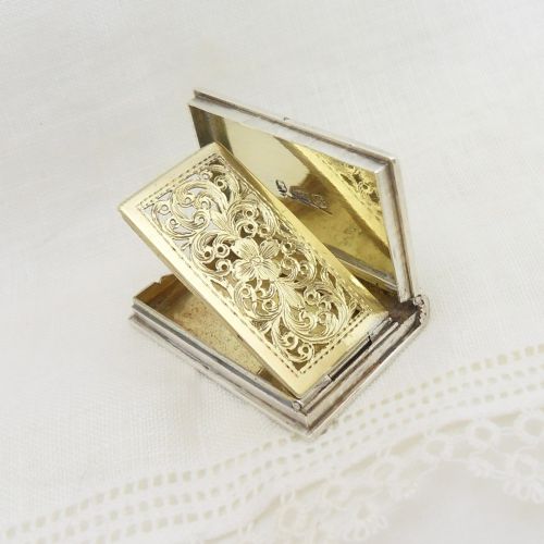 An antique sterling silver vinaigrette crafted in the form of a miniature book with an engine-turned cover, rectangular cartouche, and ribbed spine. View IV