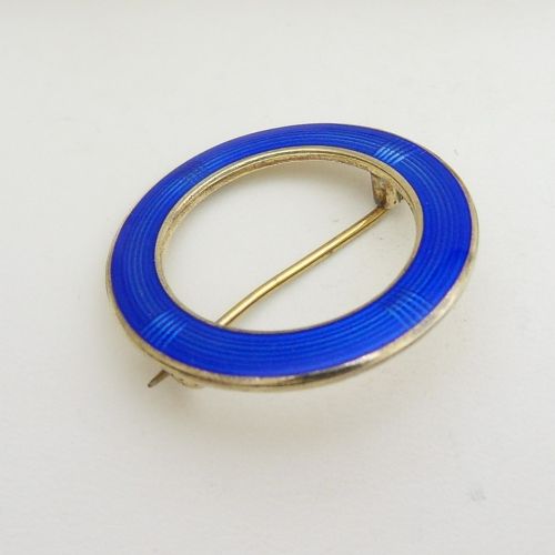 fig 1. A circular Norwegian brooch crafted in silver with vibrant cobalt blue guilloche enamel and fine geometric line patterns.