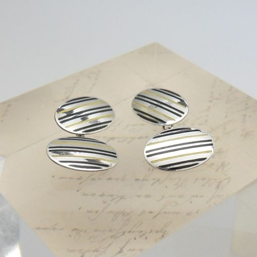 fig 1. A pair of oval sterling silver Art Deco cufflinks featuring vertical black and yellow enamel stripes connected by silver chain links.