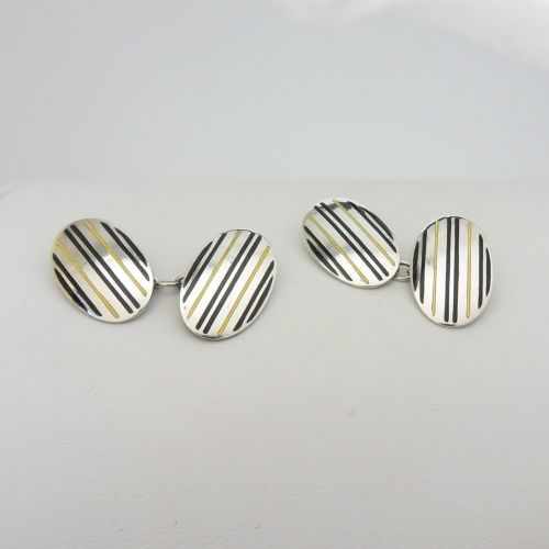 A pair of oval sterling silver Art Deco cufflinks featuring vertical black and yellow enamel stripes connected by silver chain links. View IV