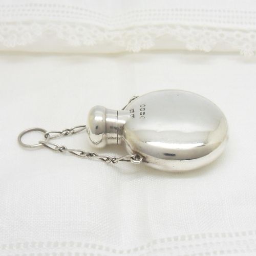 A round Victorian sterling silver miniature scent flask with a suspension chain and stamped hallmarks. View IV
