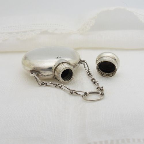 A round Victorian sterling silver miniature scent flask with a suspension chain and stamped hallmarks. View V