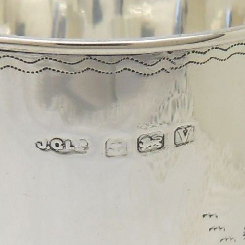 An antique sterling silver christening mug featuring an engraved foliage design and a curved handle. View IV