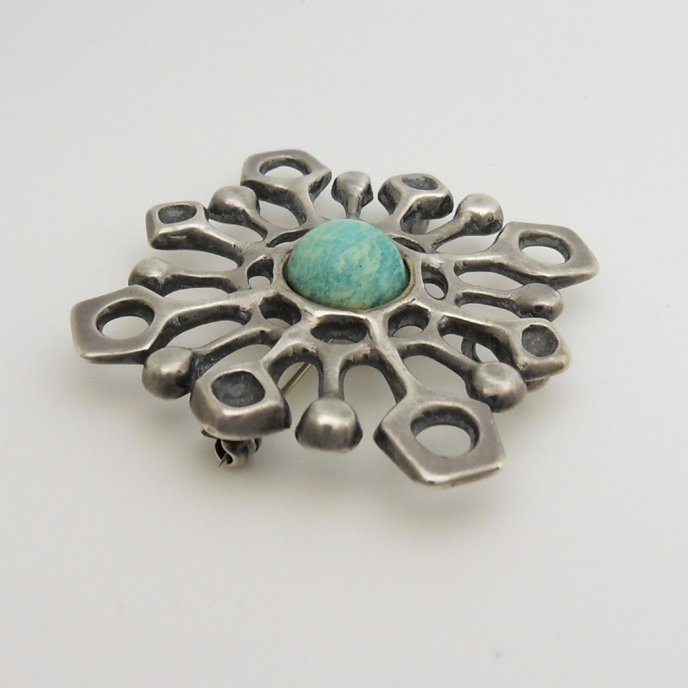 A mid-century Scandinavian openwork sterling silver pendant brooch featuring a central turquoise-green cabochon stone within a geometric starburst frame. View IV