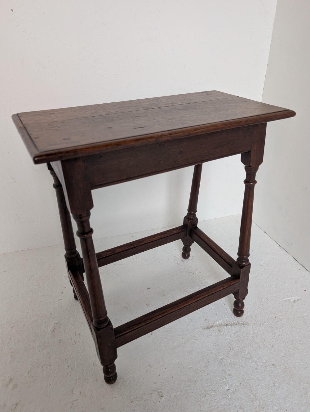 An 18th-century dark oak joint stool featuring turned legs, pegged mortise and tenon joints, and a rectangular top with low stretchers. View II