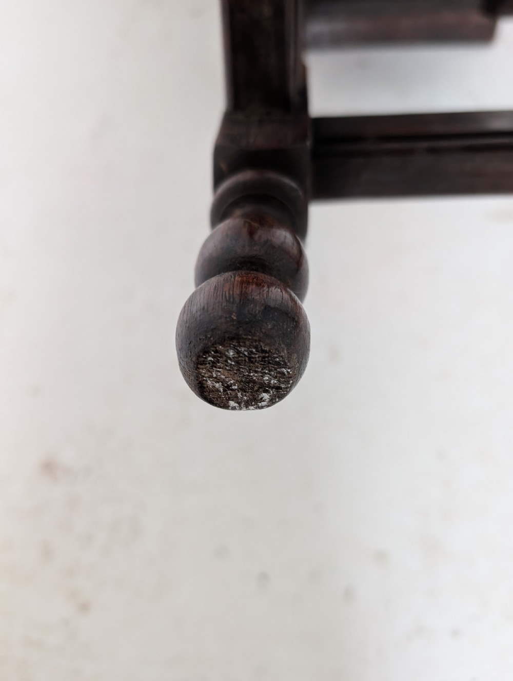 An 18th-century dark oak joint stool featuring turned legs, pegged mortise and tenon joints, and a rectangular top with low stretchers. View V