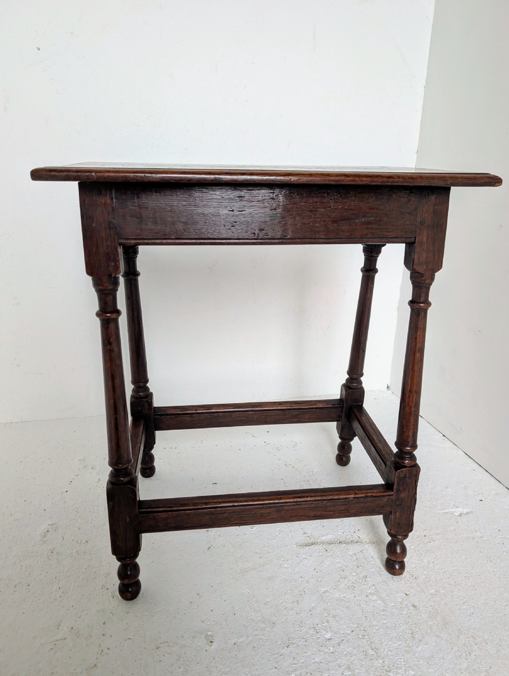 An 18th-century dark oak joint stool featuring turned legs, pegged mortise and tenon joints, and a rectangular top with low stretchers. View VIII