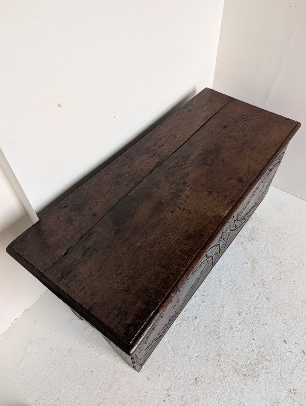 A dark oak 17th-century coffer featuring geometric hand-carved details across the front, an iron lock plate, and stile feet. View II