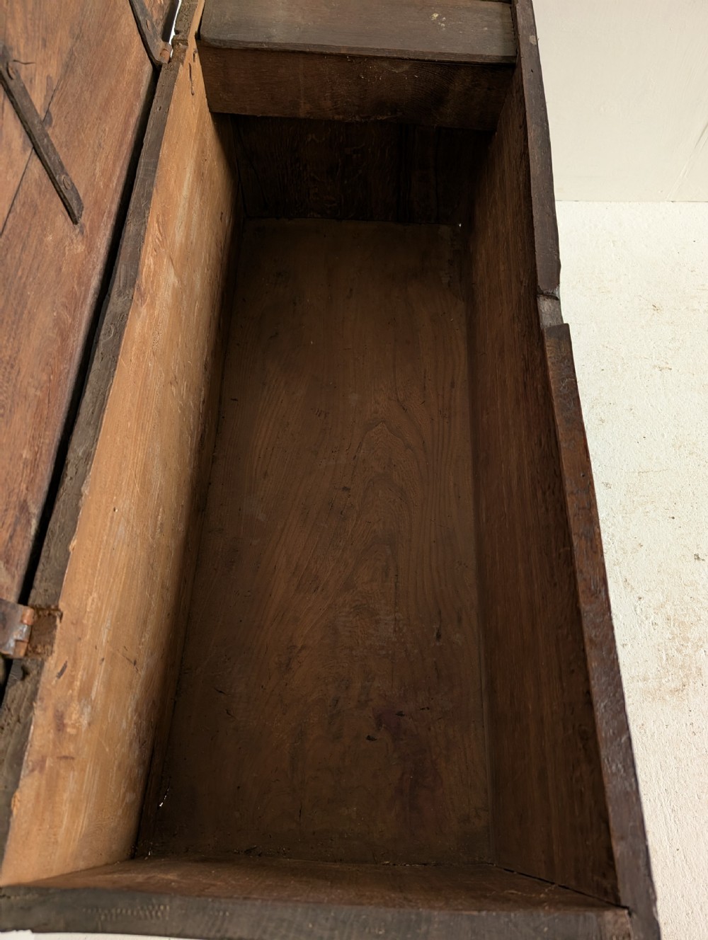 A dark oak 17th-century coffer featuring geometric hand-carved details across the front, an iron lock plate, and stile feet. View III