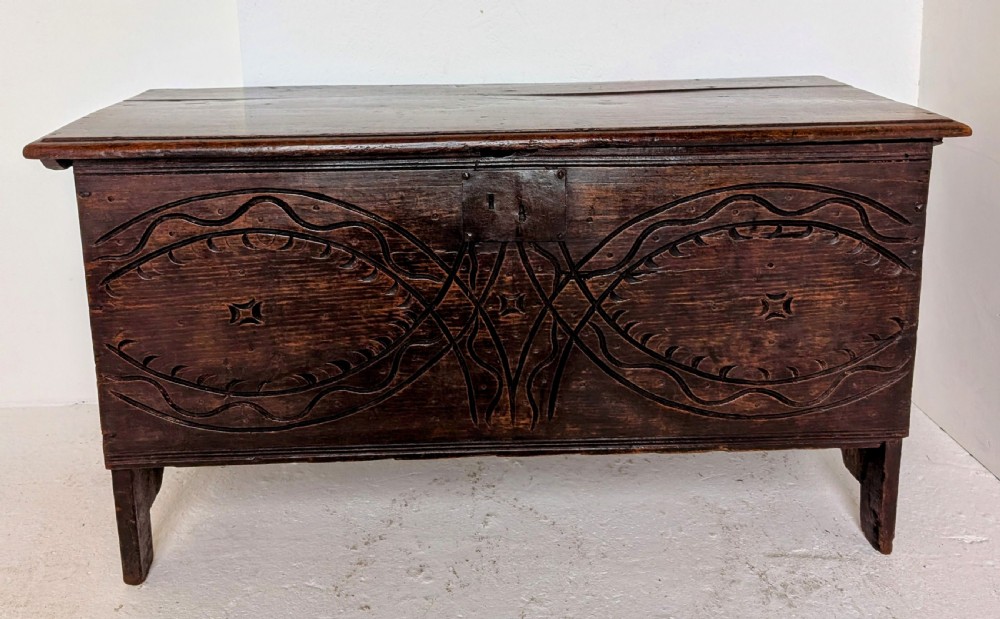 A dark oak 17th-century coffer featuring geometric hand-carved details across the front, an iron lock plate, and stile feet. View VIII
