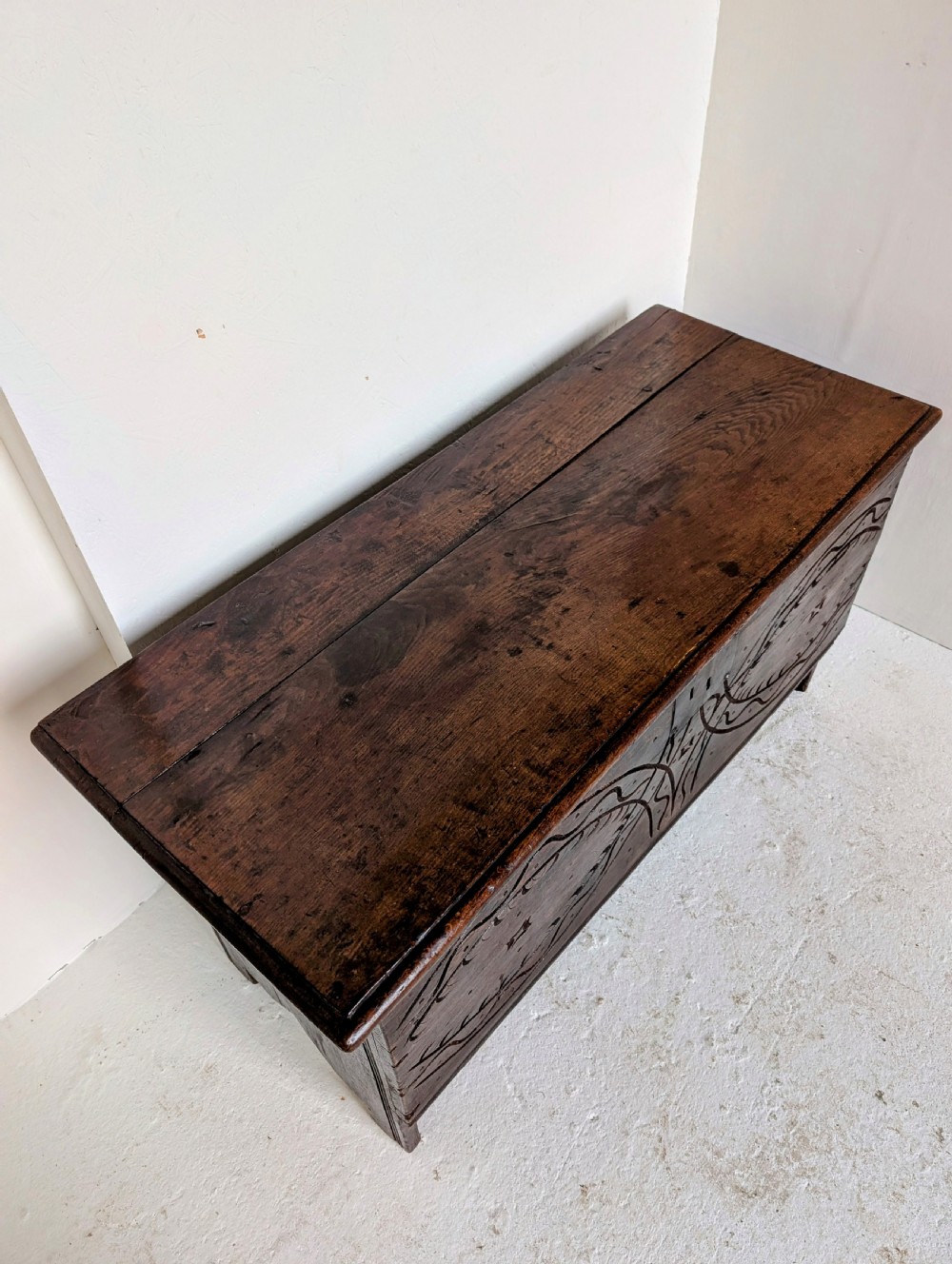 A dark oak 17th-century coffer featuring geometric hand-carved details across the front, an iron lock plate, and stile feet. View IX