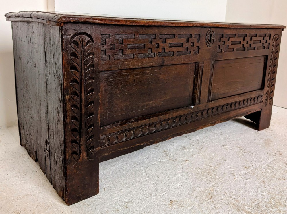 A seventeenth-century dark oak coffer featuring carved leaf stiles, geometric fretwork, and a panelled front structure. View VIII