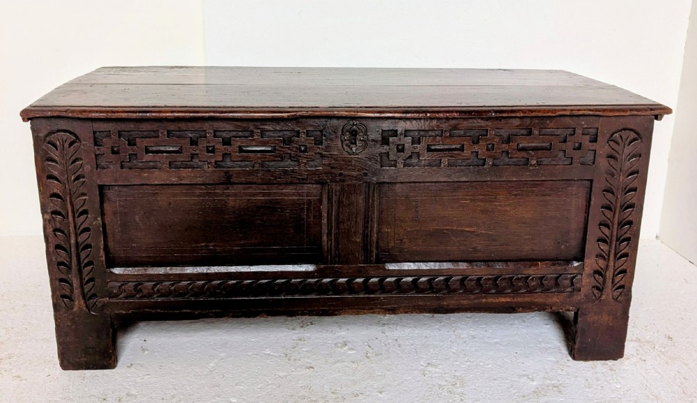 A seventeenth-century dark oak coffer featuring carved leaf stiles, geometric fretwork, and a panelled front structure. View IX