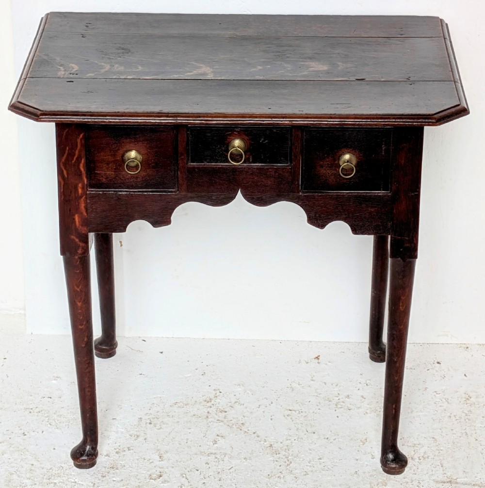 An 18th-century dark oak lowboy table featuring three drawers with brass ring pulls, a scalloped apron, and cabriole legs ending in pad feet. View VI