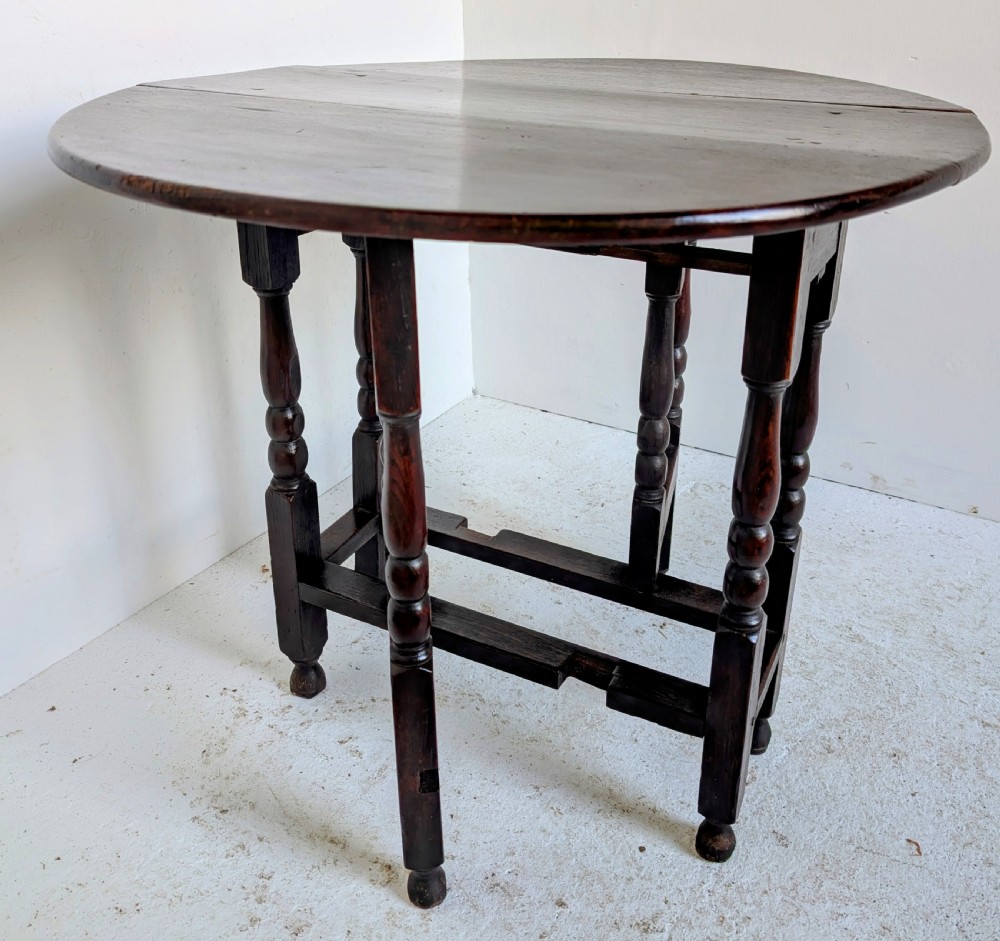 A dark oak 17th-century gateleg table with two drop-leaf flaps, turned baluster legs, and low box stretchers. View II
