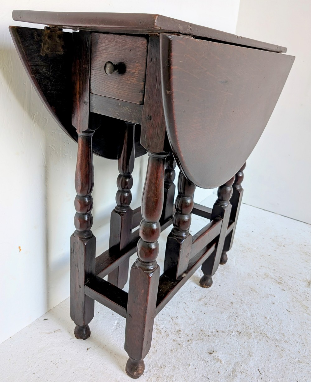 A dark oak 17th-century gateleg table with two drop-leaf flaps, turned baluster legs, and low box stretchers. View IV