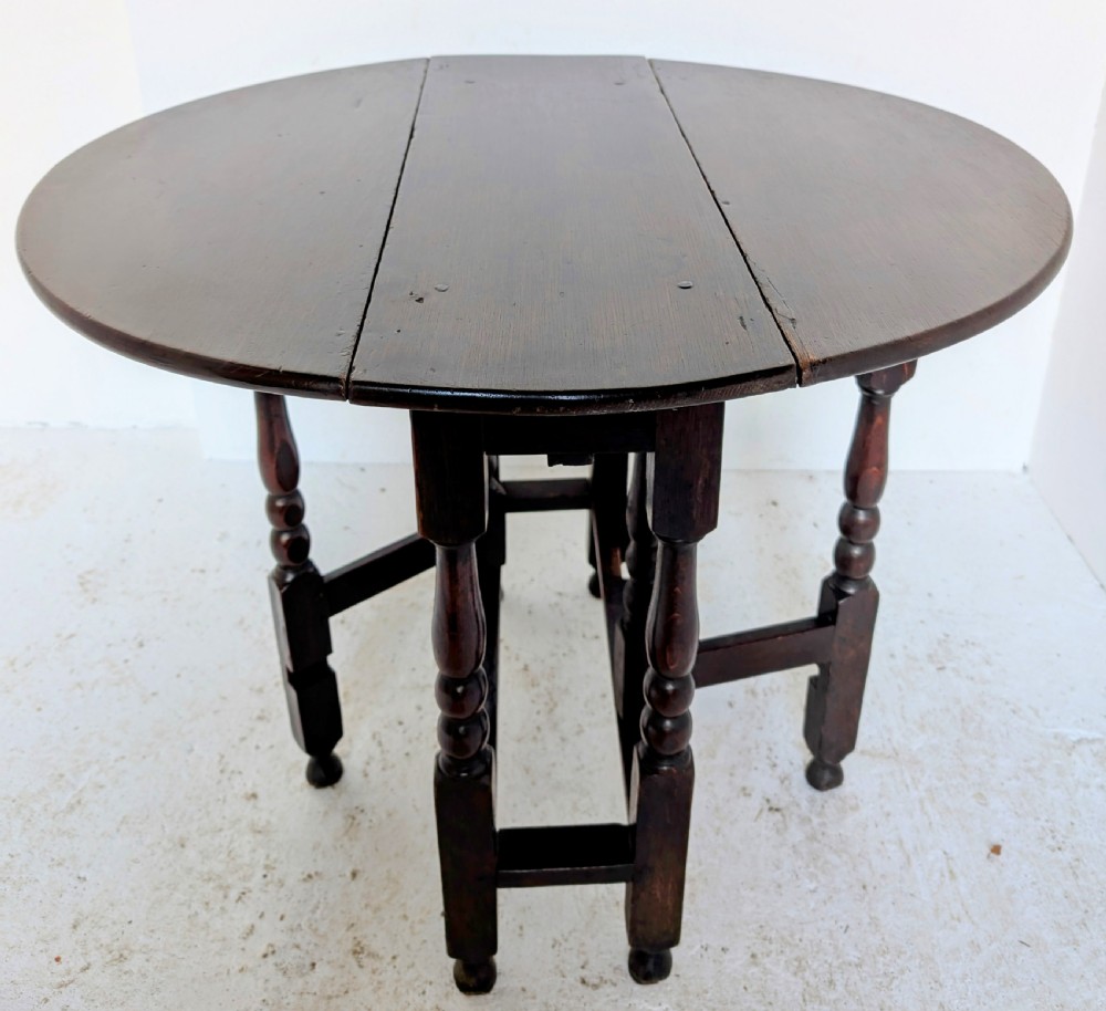 A dark oak 17th-century gateleg table with two drop-leaf flaps, turned baluster legs, and low box stretchers. View V